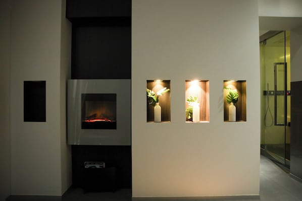 Ein modernes Interieur mit Kamin, Einbauleuchten und Topfpflanzen.