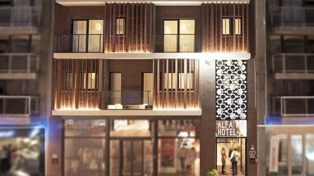 Un hotel moderno con fachada de dos pisos, amplias ventanas y una entrada visible con un letrero.