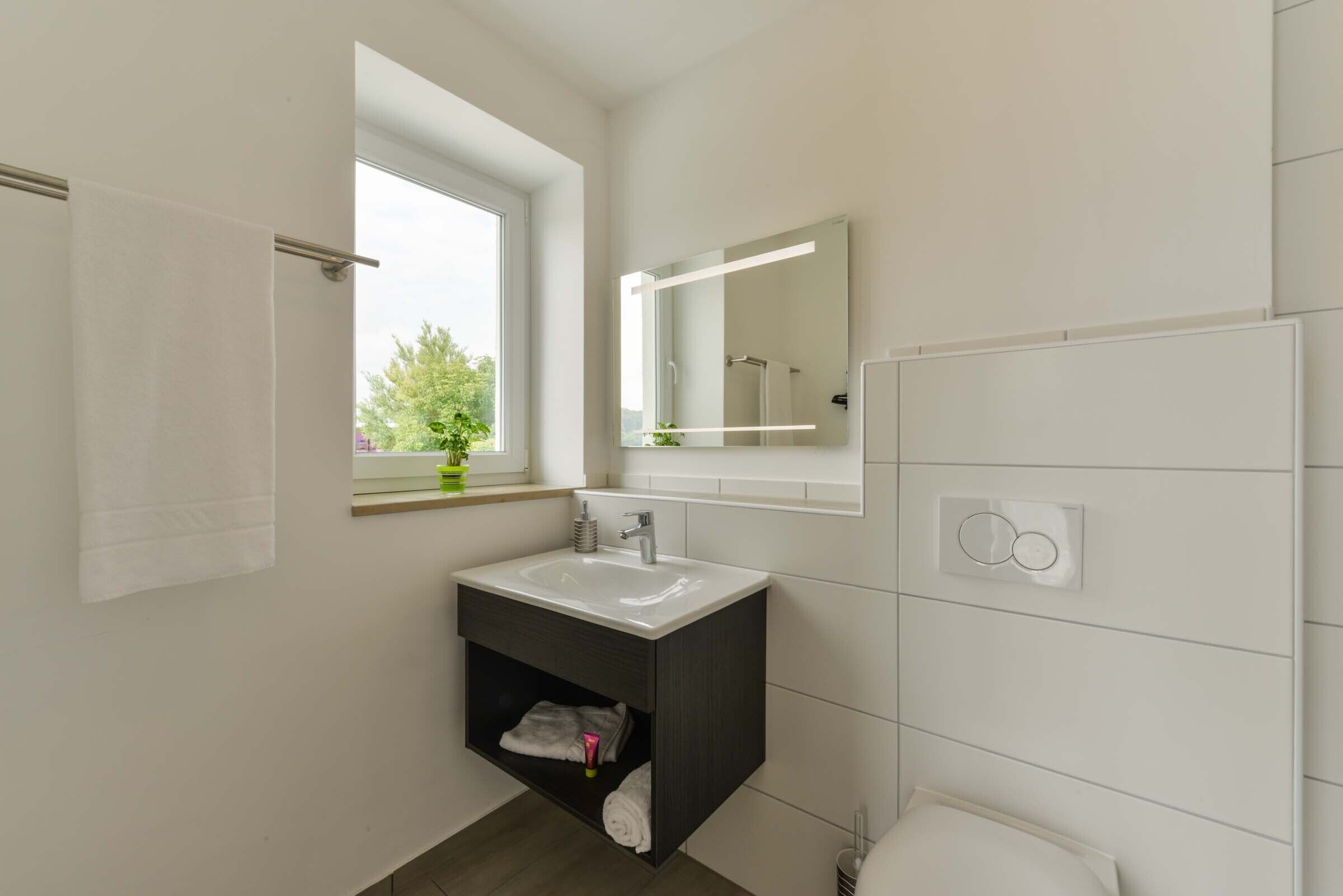 A modern bathroom with a white sink, dark vanity, and a large mirror.