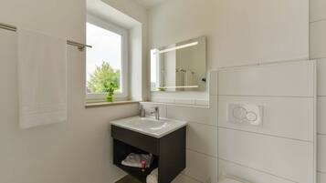 A modern bathroom with a white sink, dark vanity, and a large mirror.