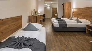 Et hotelværelse med to senge, trægavle, et skrivebord og en stol.