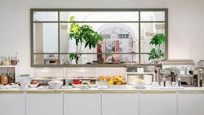 Una cocina moderna con un amplio ventanal, diversos alimentos sobre la encimera y una cafetera.