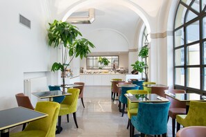 A modern restaurant with colorful chairs and tables, large windows, and potted plants. - Hotel Horto Convento (Florence)