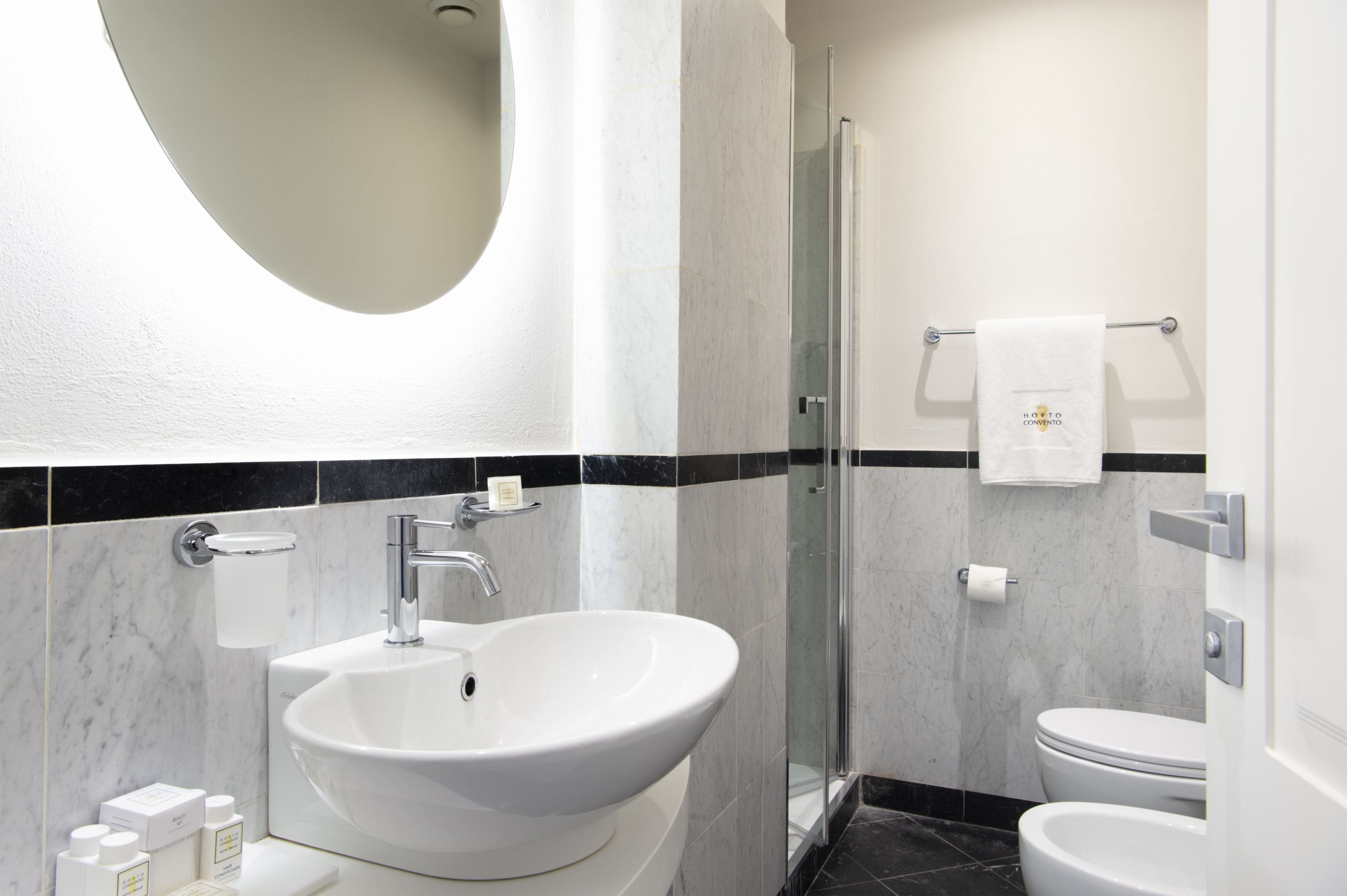 A modern bathroom with a large oval sink, a glass shower enclosure, and a toilet.