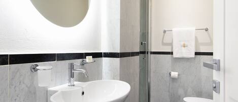 A modern bathroom with a large oval sink, a glass shower enclosure, and a toilet.