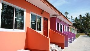 Une rangée de bâtiments aux couleurs vives, avec un escalier menant à une porte, des palmiers en arrière-plan et un ciel dégagé.