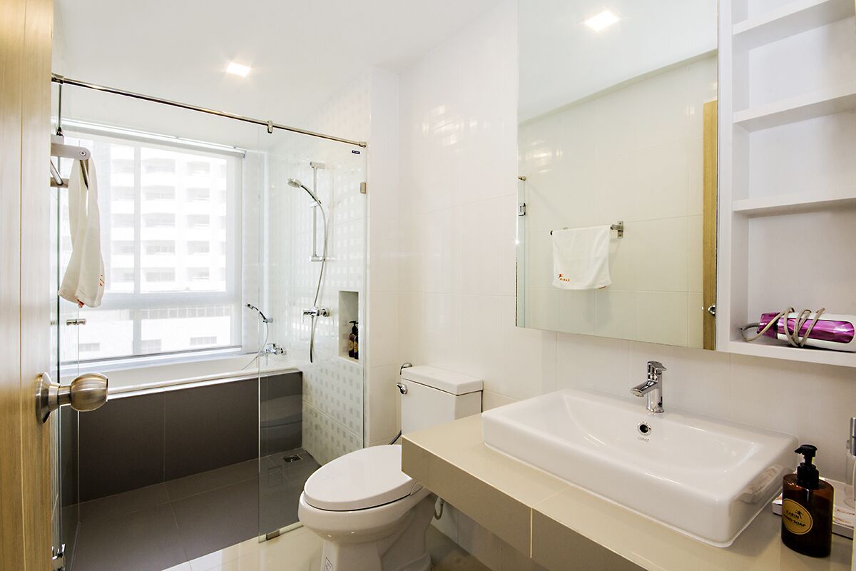 Een moderne badkamer met een douchecabine van glas, een witte wastafel en een toilet.
