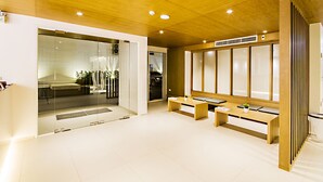 Een moderne hotel lobby met een houten plafond, een receptiebalie, een zithoek en uitzicht op de straat.