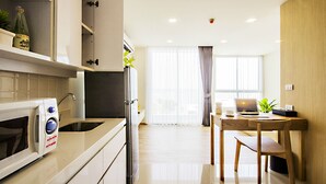 Een moderne keuken met een magnetron, gootsteen en kastjes. Er is een zithoek met een tafel en stoelen.