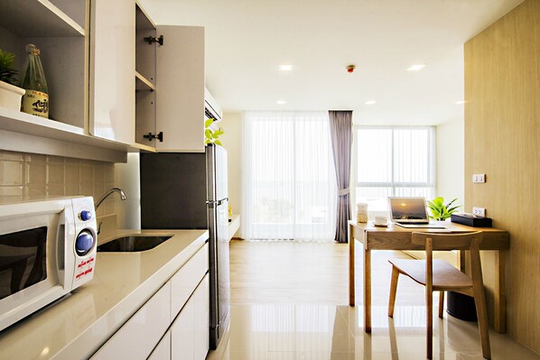 Una cocina moderna con microondas, pileta y armarios. Hay un comedor con mesa y sillas.