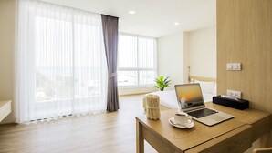 Een moderne hotelkamer met een houten bureau, een laptop, een kopje en een plant.