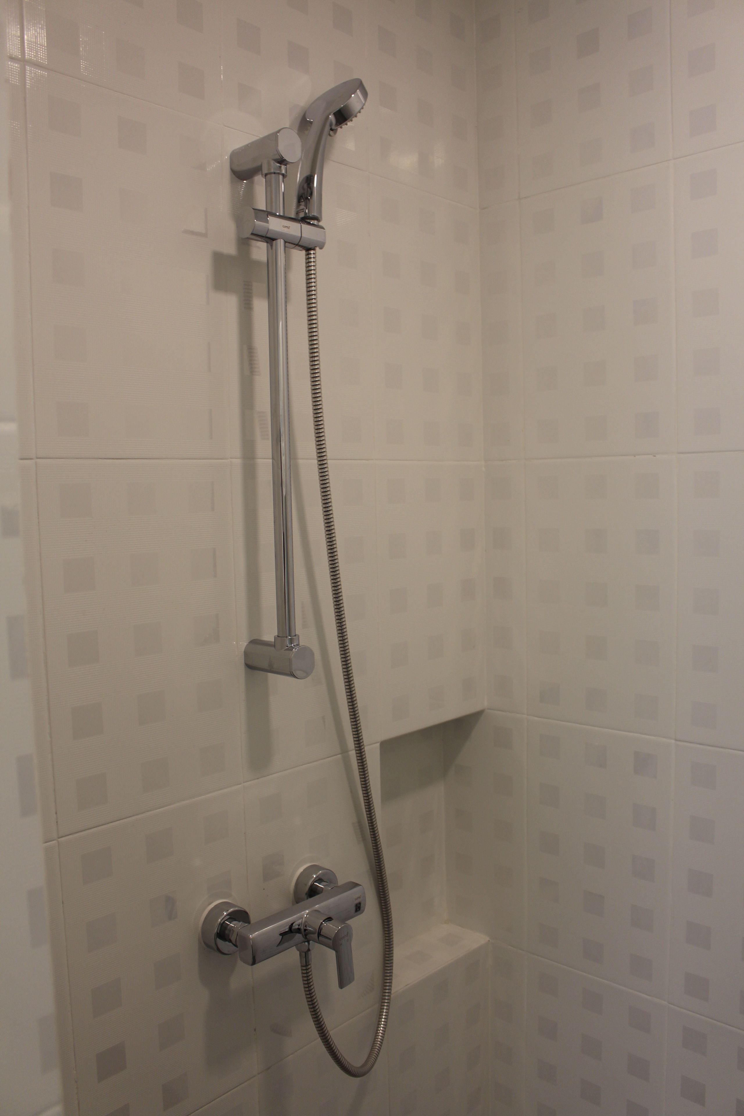 A shower with a handheld showerhead and a handheld hose.