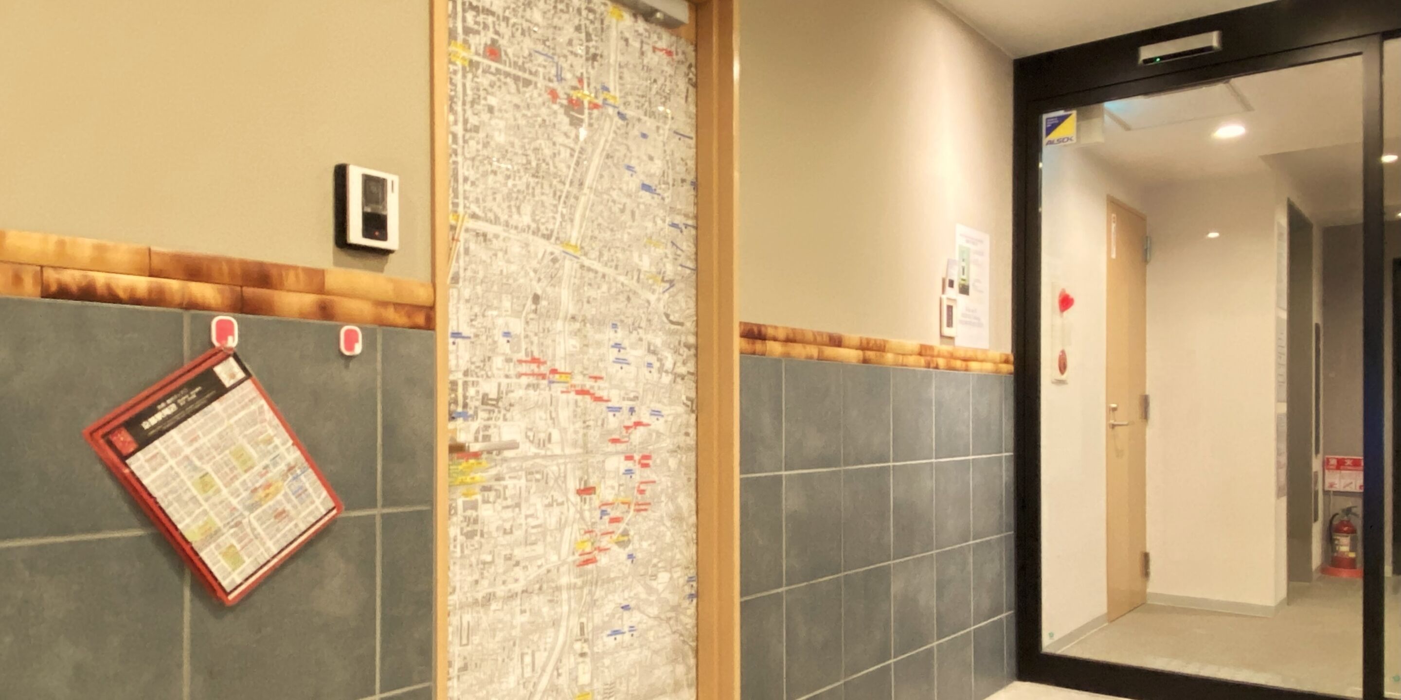 A hotel lobby with a map on the wall, a fire extinguisher, and a door to a room.