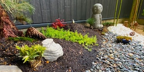 Stroll through a serene garden oasis, featuring a tranquil statue and lush greenery.