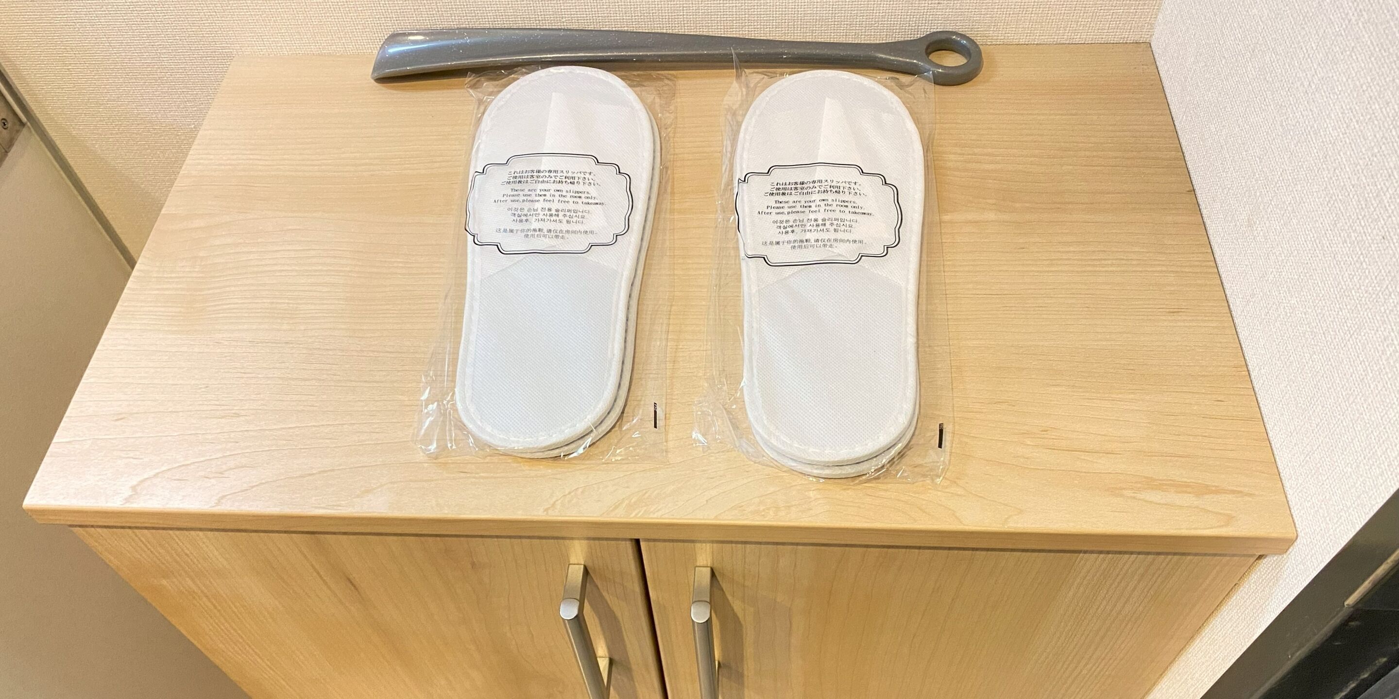 Two white slippers with labels on a wooden surface.