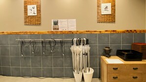 Ein Badezimmer mit gefliesten Wänden, einem Handtuchhalter mit Regenschirmen, einem Holzschrank und zwei an der Wand befestigten Schildern.