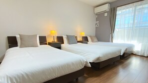 Ein Hotelzimmer mit zwei Betten, Nachttischlampen, einer Klimaanlage und einem großen Fenster mit Vorhängen.