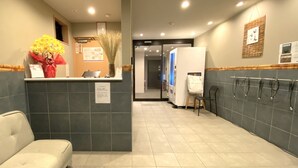 Ein Empfangsbereich mit Empfangstresen, einem Sessel, einem Blumenstrauß, einer Pinwand und einem an der Wand befestigten Schild.