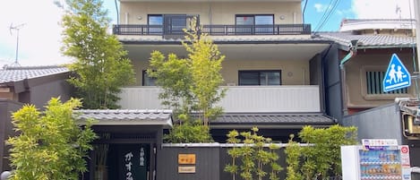 A two-story building with a balcony, a vending machine, and a pedestrian crossing sign.