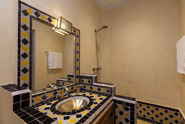 A bathroom with a sink, mirror, and shower.