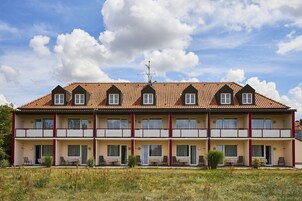 Un hotel de varios pisos con techo de tejas, balcones y zonas de estar al aire libre.