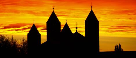 A silhouette of a church with multiple spires against a sunset sky.