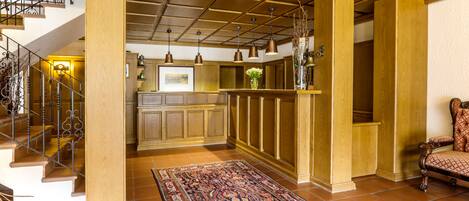 Amplia sala de estar con un tapete grande, una escalera y una cocina con armarios de madera e iluminación colgante.