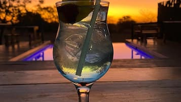 Ett cocktailglas med sugrör och en limeskiva på ett träbord.