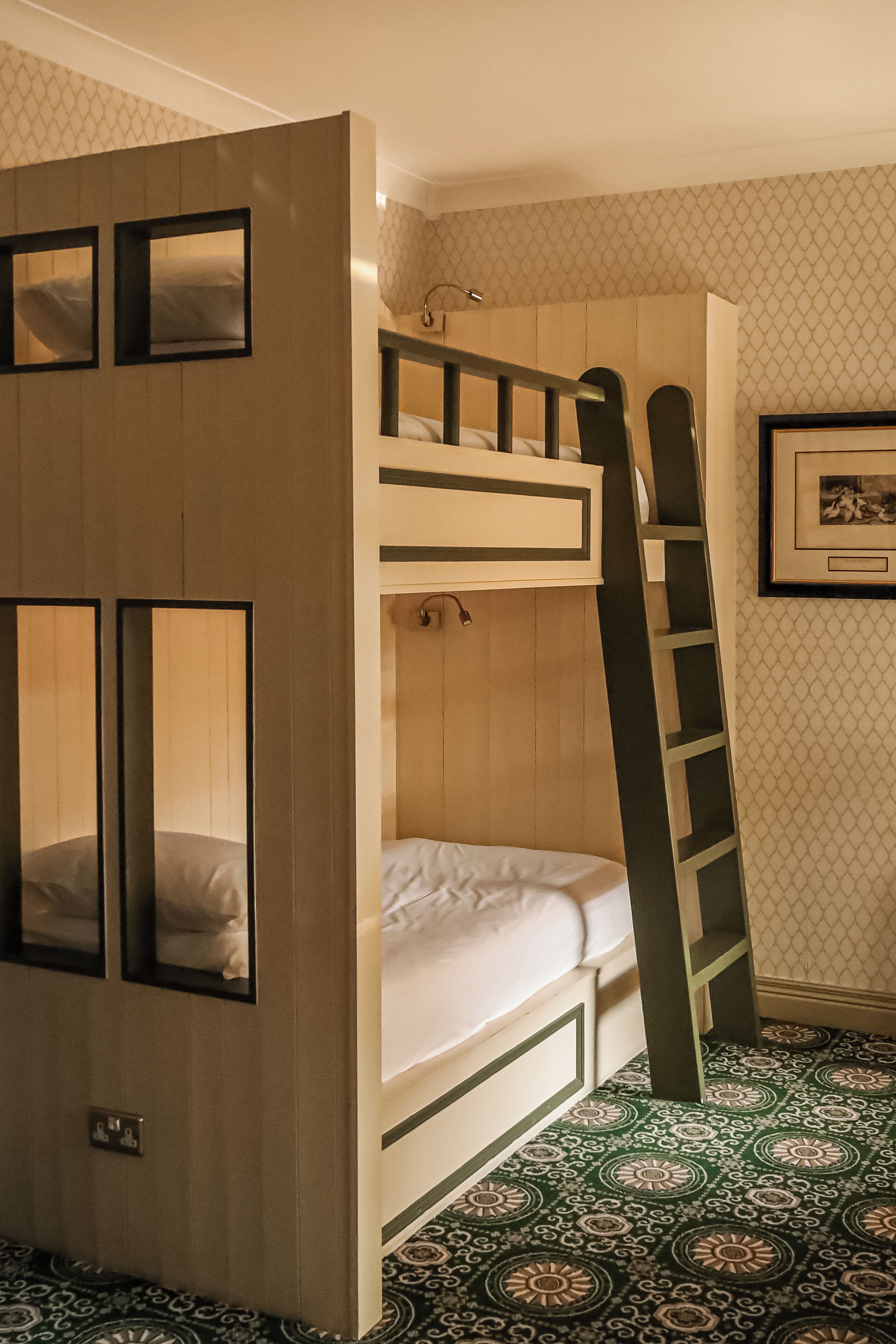 Een slaapkamer met een stapelbed, een klein bureau en een lijst met foto aan de muur.