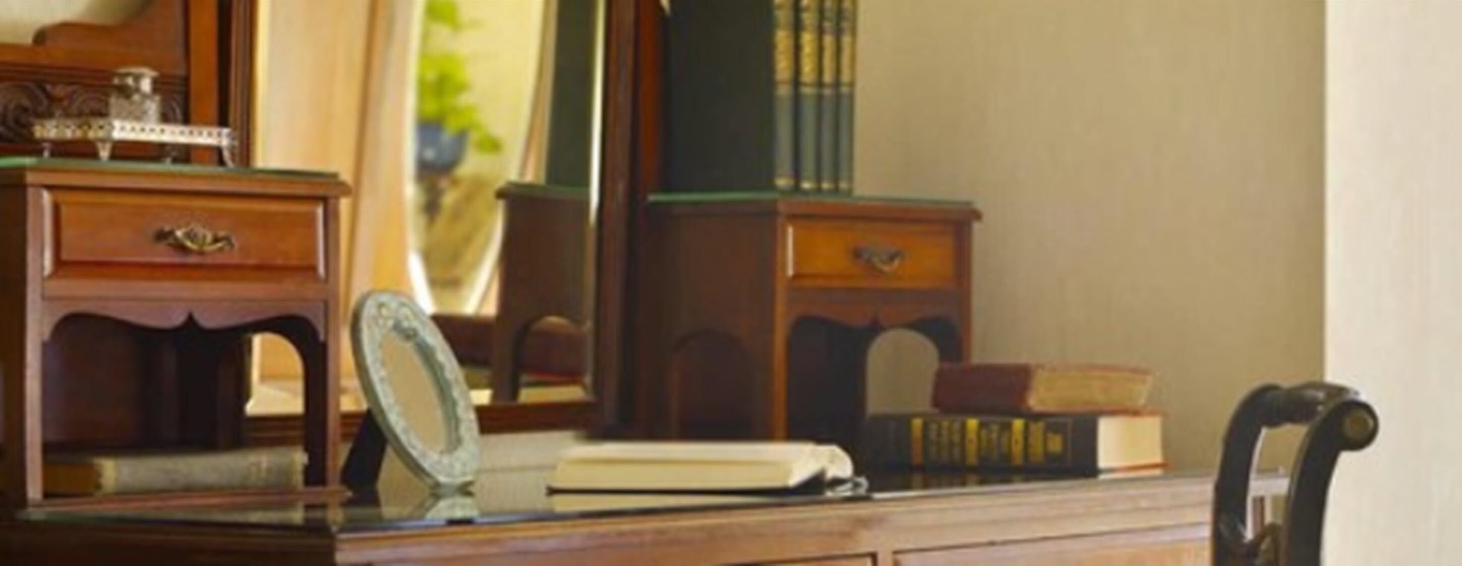 A wooden dresser with a mirror, a book, and a small decorative item.