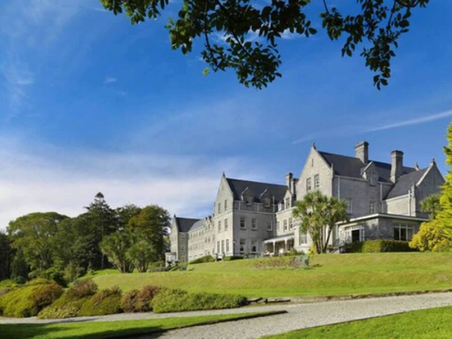 A large, historic building with multiple wings and a well-maintained lawn.