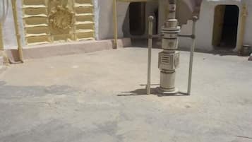 A courtyard with a water fountain, a gate, and a building with arched doorways.