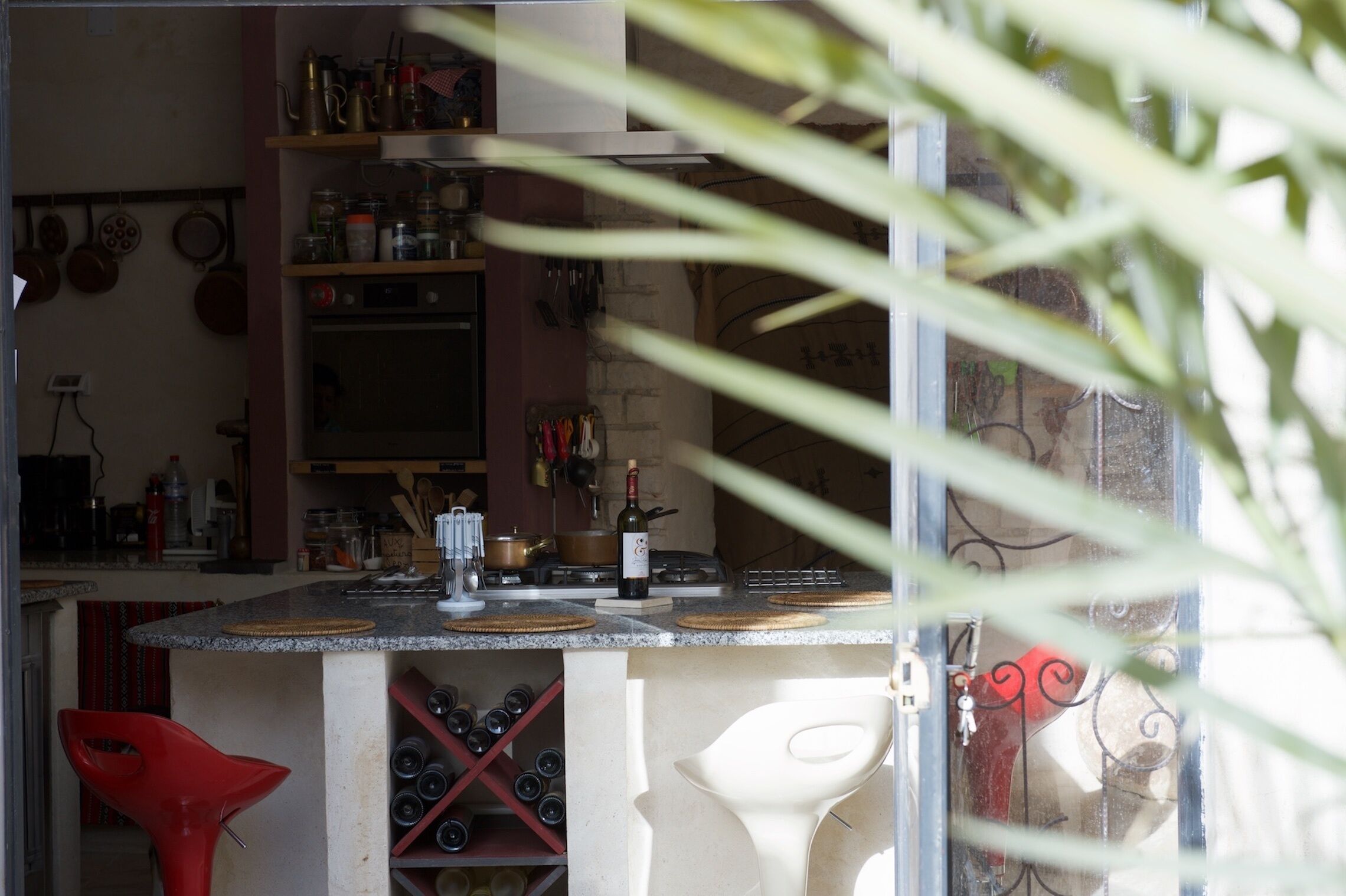 Una cocina con mostrador, un botellero y varios utensilios de cocina.