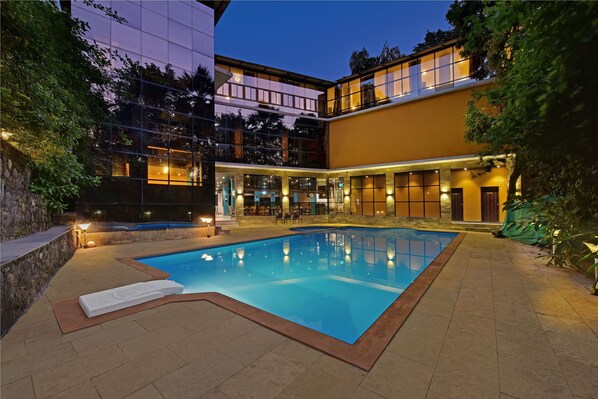 A modern hotel with a swimming pool, outdoor seating, and a well-lit courtyard. - Silvanus Forest Retreat (Alibag)