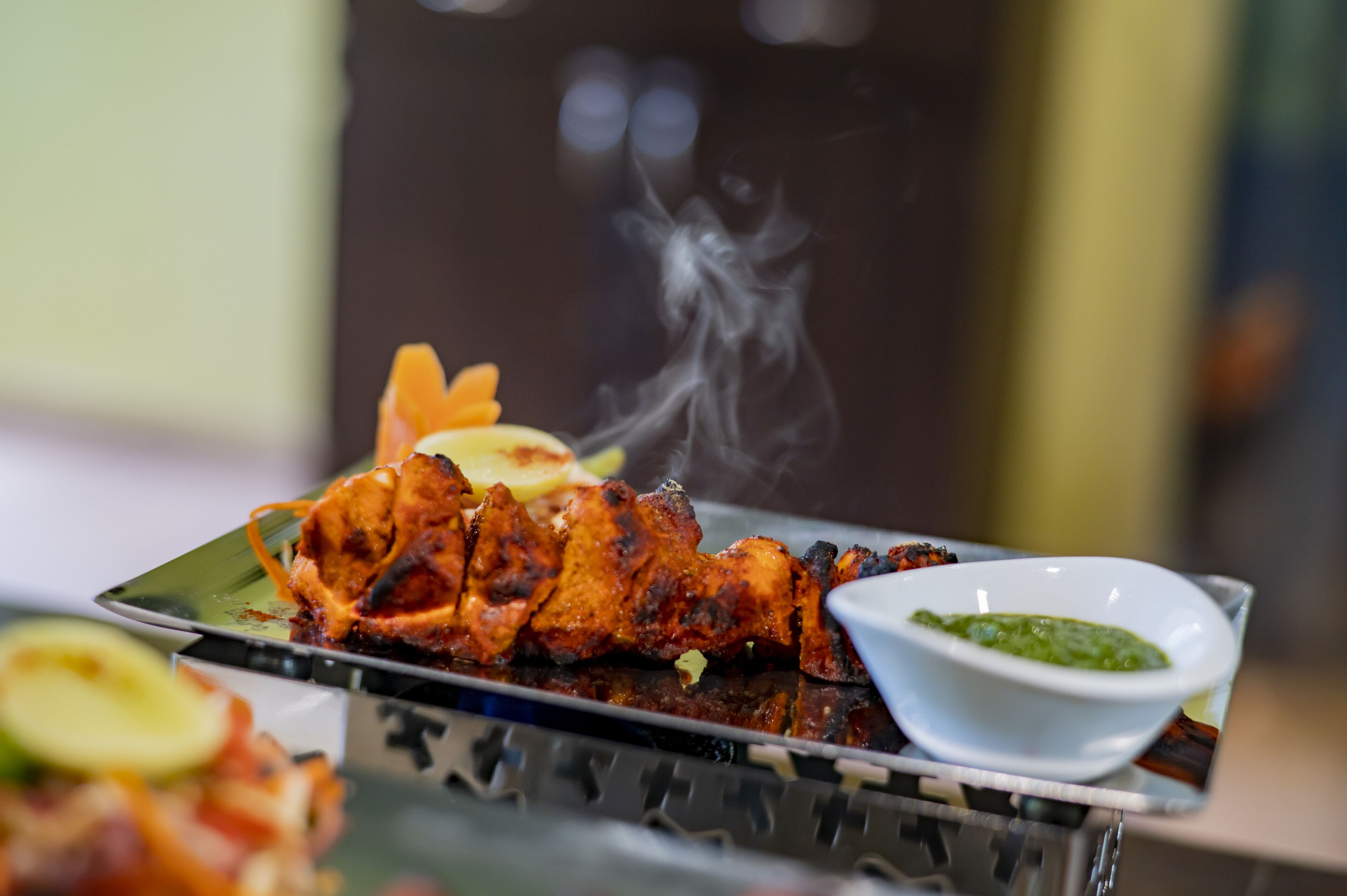 Un plato de pollo tandoori acompañado de chutney verde.