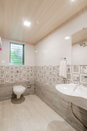 A modern bathroom with a toilet, sink, and a window. - Silvanus Forest Retreat (Alibag)