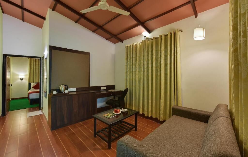 A compact living space with a sofa, a small table, a desk with a chair, and a ceiling fan.