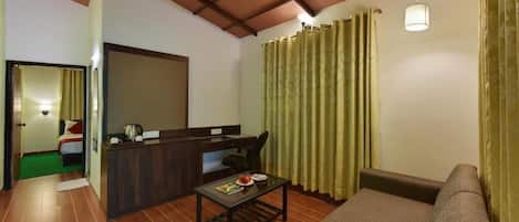 A compact living space with a sofa, a small table, a desk with a chair, and a ceiling fan.