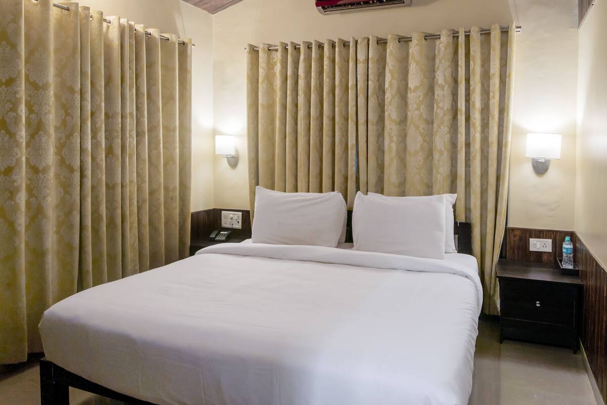 Une chambre d’hôtel avec un grand lit, deux tables de chevet et des rideaux.