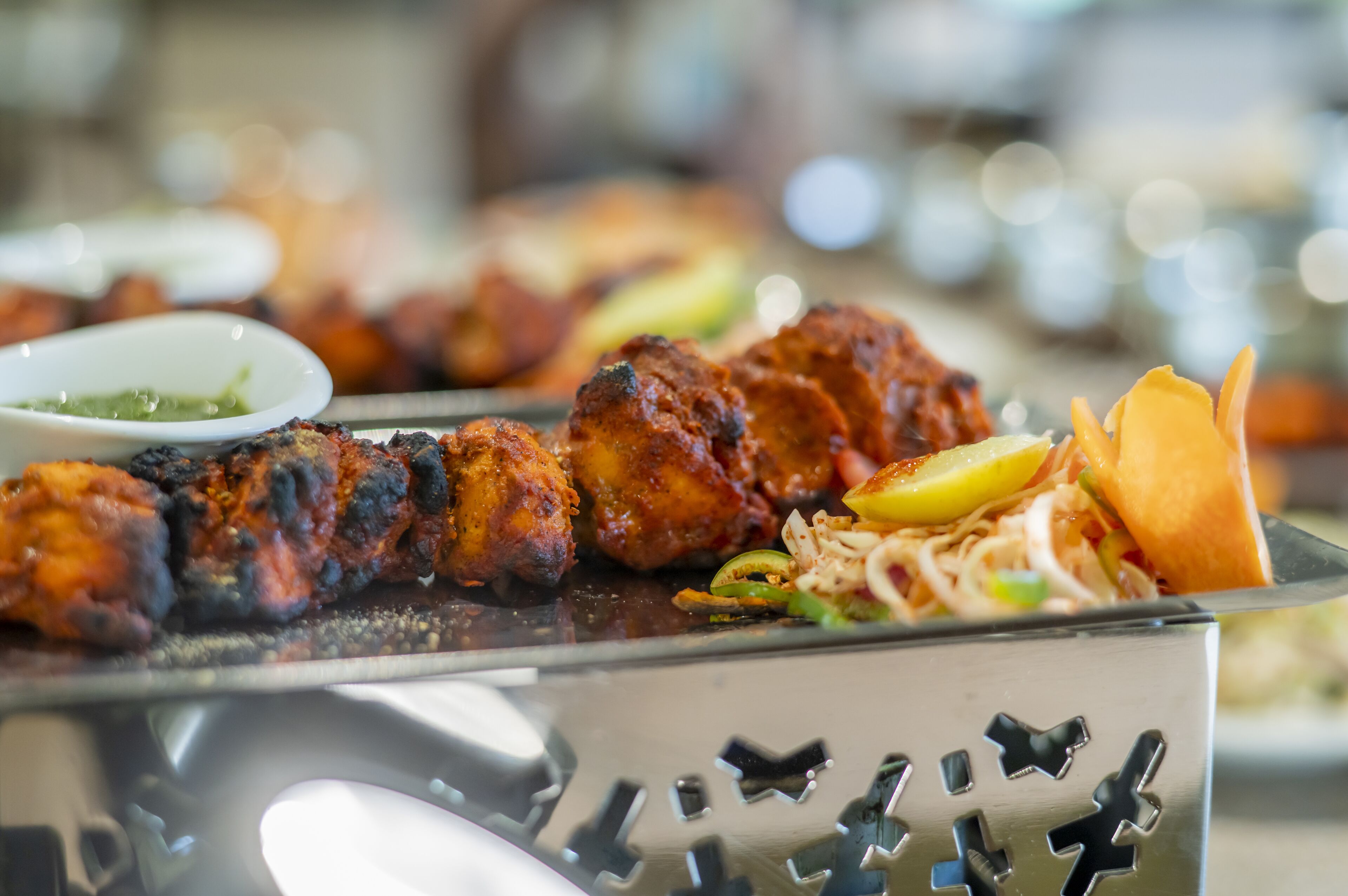 Ein Buffet mit verschiedenen Speisen, darunter gegrilltes Fleisch, Salat und eine Soße.