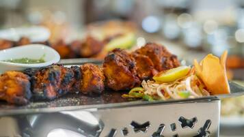 A buffet with various dishes including grilled meat, a salad, and a bowl of sauce.
