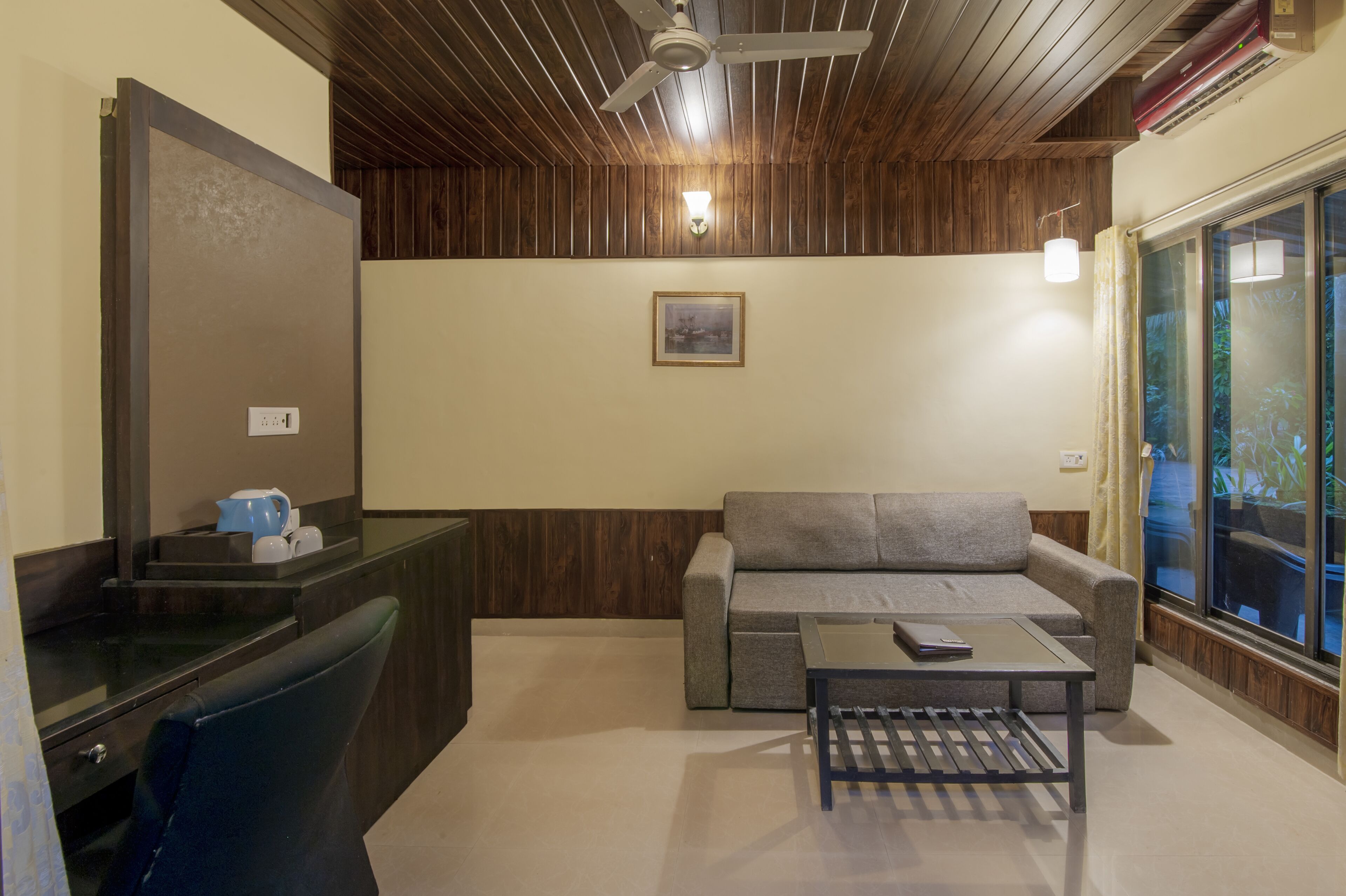 A room with a wooden ceiling, a sofa, a coffee table, and a window with curtains.