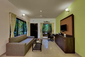 A living room with a sofa, coffee table, TV, and a reception desk. - Silvanus Forest Retreat (Alibag)