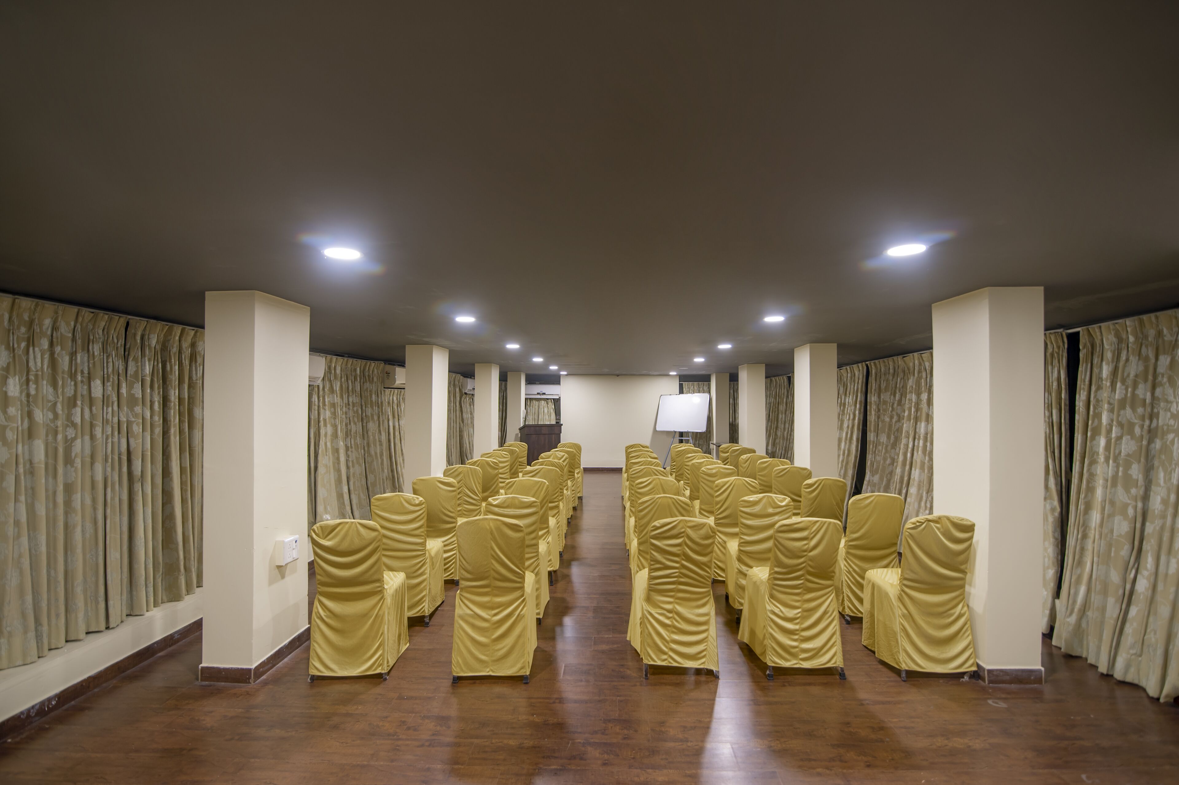 Un salón de conferencias con filas de sillas, un atril y una pantalla de proyector.