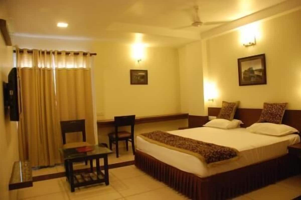 Ein Hotelzimmer mit Bett, Schreibtisch, Stuhl und Vorhang.