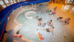 Een binnenzwembad met meerdere banen en een centraal deel met whirlpools.