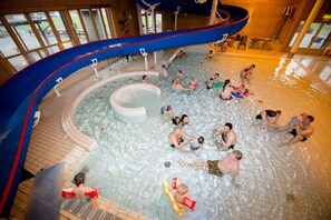 Ein Hallenbad mit mehreren Bahnen und einem zentralen Whirlpool-Bereich.