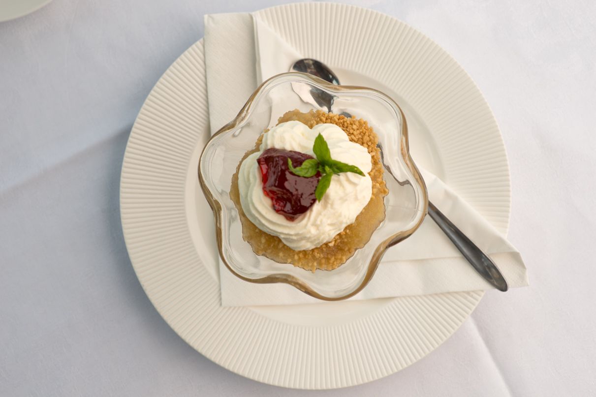 A dessert on a white plate with a spoon and napkin.