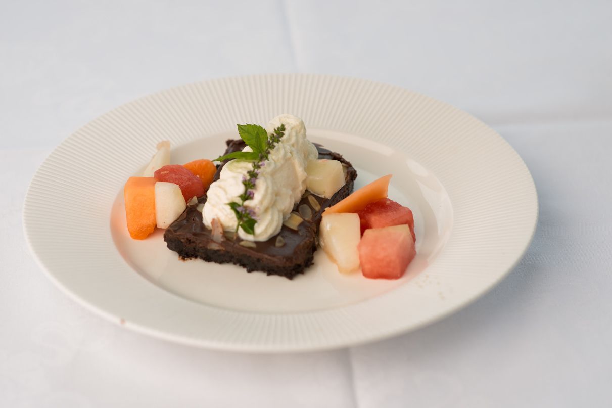 Um prato de sobremesa com bolo de chocolate, sorvete e frutas em um prato branco.