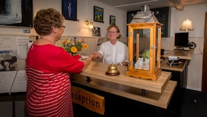A reception desk with a wooden cabinet, a bell, and a sign that reads "reception". - Femo Kro & Feriecenter by DanCenter (Maribo)
